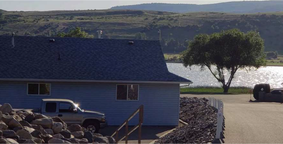 View of Swan Lake Professional Home Inspection Report PDF Example | At Ease Property Inspections A single-story residential or commercial structure with a dark blue roof and light siding, located on the shore of Swan Lake near Vernon, BC. A pickup truck is parked nearby, and a hillside is visible in the background. Erich Kamprath/At Ease Property Inspections provides expert inspection services for all types of Modular Home Parks and waterfront properties throughout the Spallumcheen Valley and North Okanagan.
